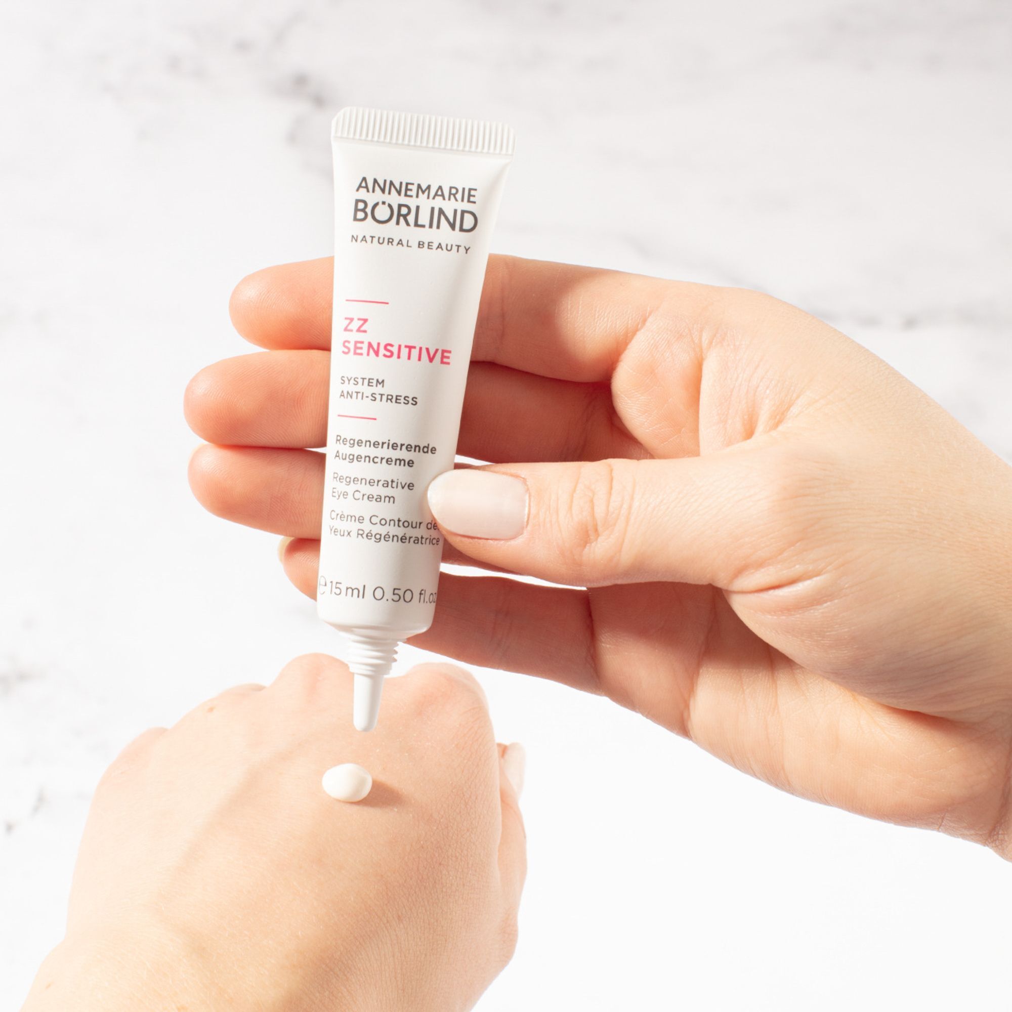 Hand hält ANNEMARIE BÖRLIND ZZ SENSITIVE Augencreme-Tube über Handfläche, ein Tupfer Creme.