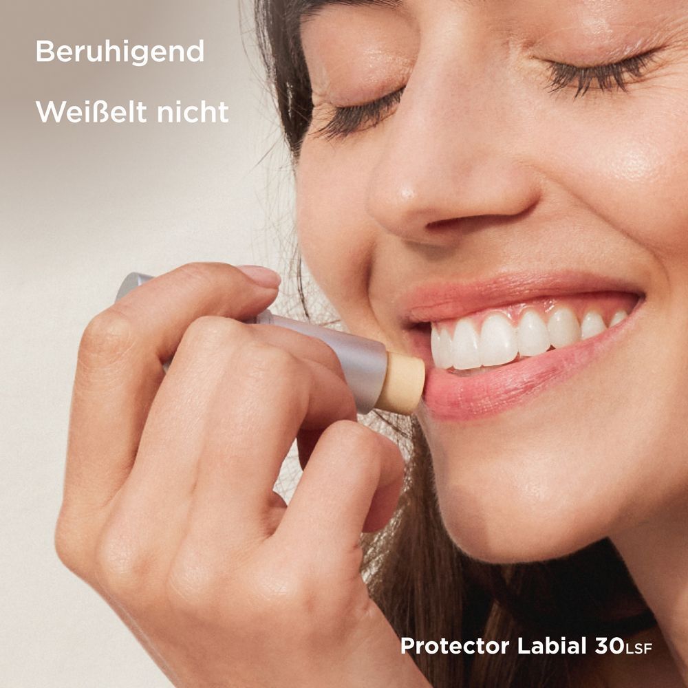 Frau trägt Lippenpflege auf. Text: Beruhigend, weißelt nicht. Aufschrift: Protector Labial 30 LSF.