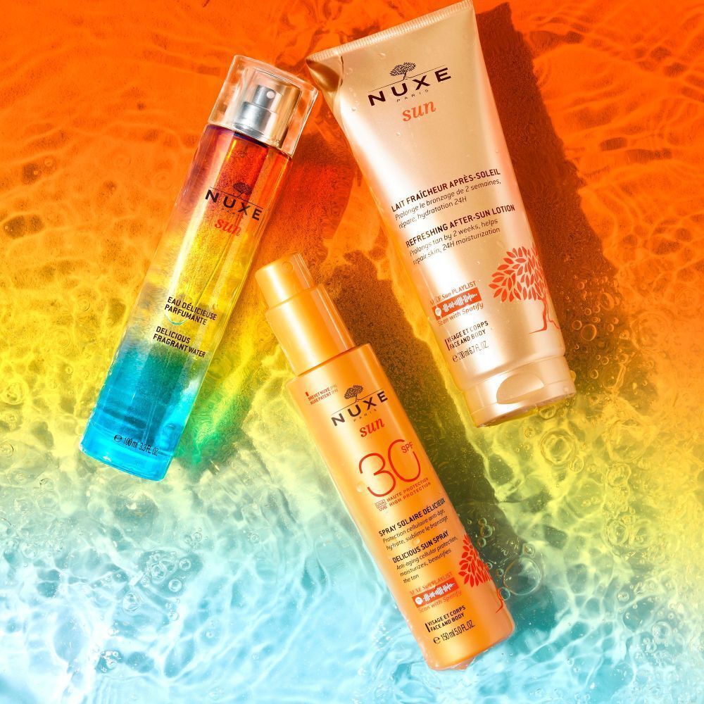 Drei Produkte: Flakon, Spray und Tube. Farbverlauf von blau nach orange. Text: NUXE Sun, Spray Solaire, Lait Fraîcheur Après-Soleil.