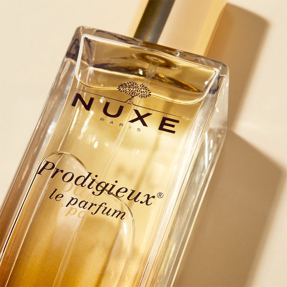 Nahaufnahme eines Glasflakons mit goldener Kappe. Aufschrift: NUXE Paris, Prodigieux le parfum.