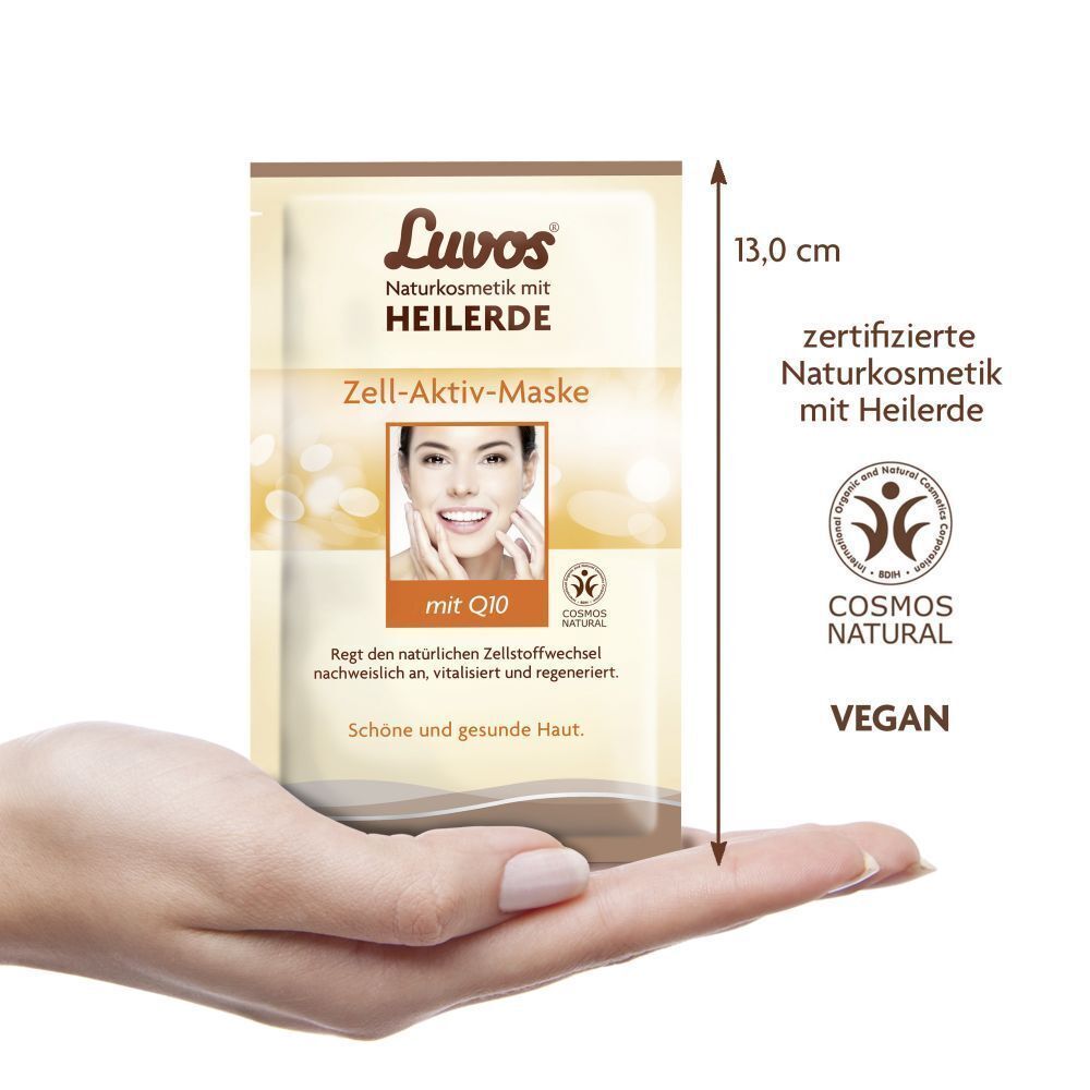 Eine Hand hält einen Beutel Luvos Heilerde Zell-Aktiv-Maske. Aufdruck: Logo, Produktname, Frauengesicht, Q10, Naturkosmetik, Vegan. 13,0 cm.