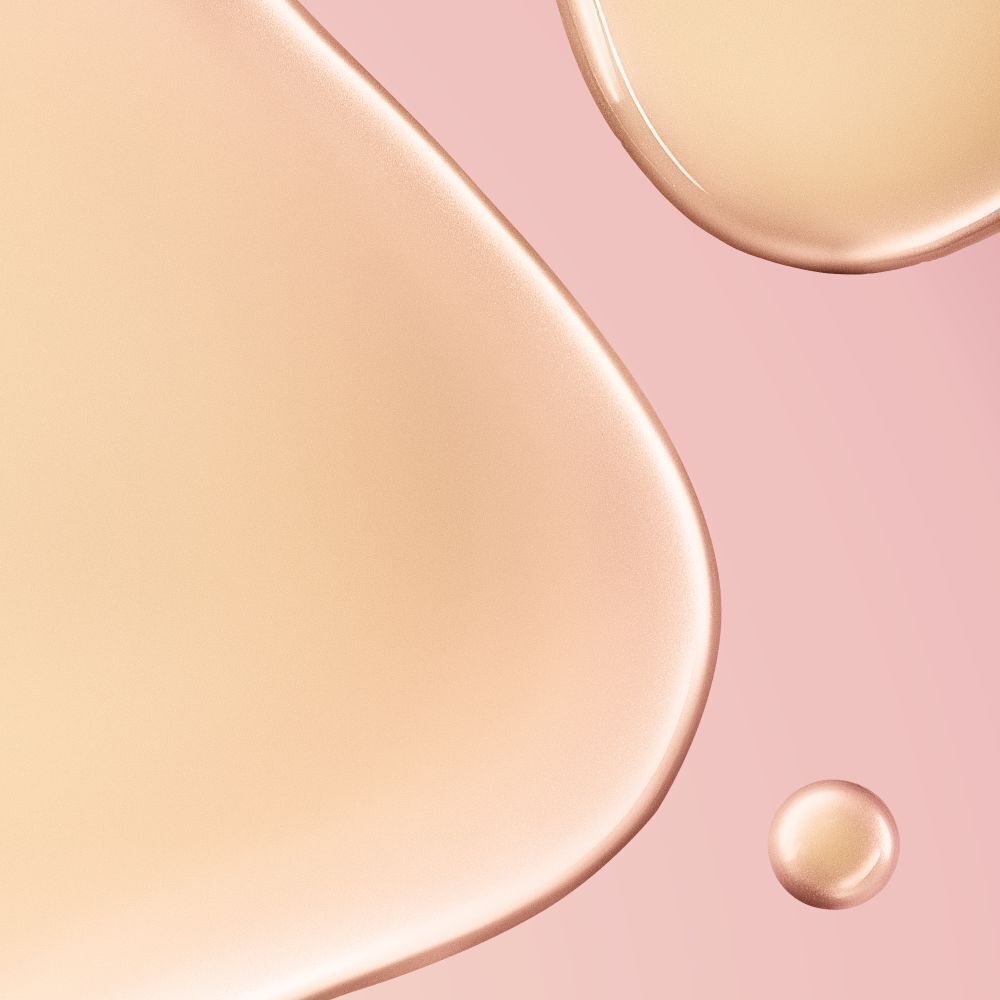 Nahaufnahme von Tropfen einer Flüssigkeit auf rosa Hintergrund. Runde und ovale Formen. Farbton: hellbraun.
