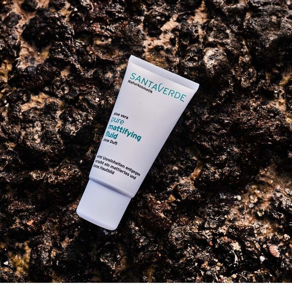 Eine Tube SANTAVERDE mattifying fluid auf Stein. Weiße Tube mit grüner Schrift. Aufschrift: pure mattifying fluid, ohne Duft.