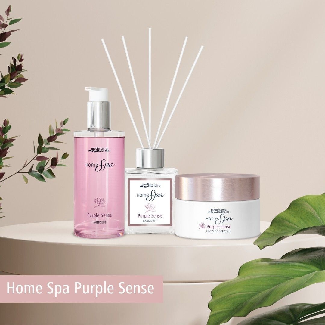 Drei Produkte: Raumduft, Körperlotion und Duschgel. Aufschrift: HOME Spa Purple Sense. Marke: medipharma cosmetics. Auf einem Podest mit Blättern.