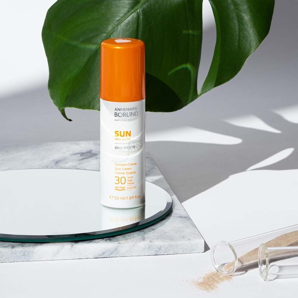 ANNEMARIE BÖRLIND Suncare Face DNA Protect LSF 30 neben einem Spiegel und Blatt.
