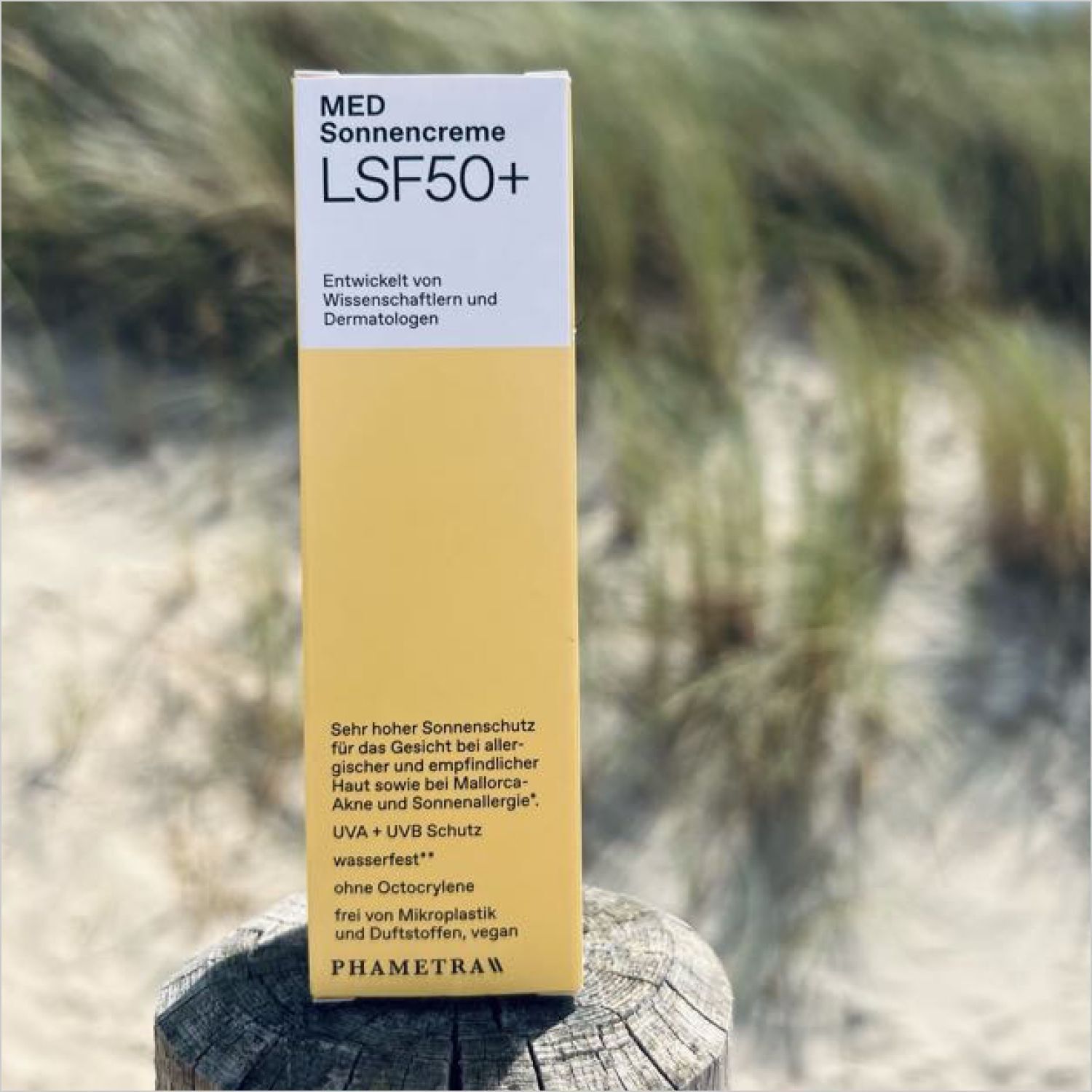 Gelbe Verpackung von PHAMETRA MED Sonnencreme LSF 50+ auf einem Holzpfosten. Text: MED Sonnencreme, LSF 50+.