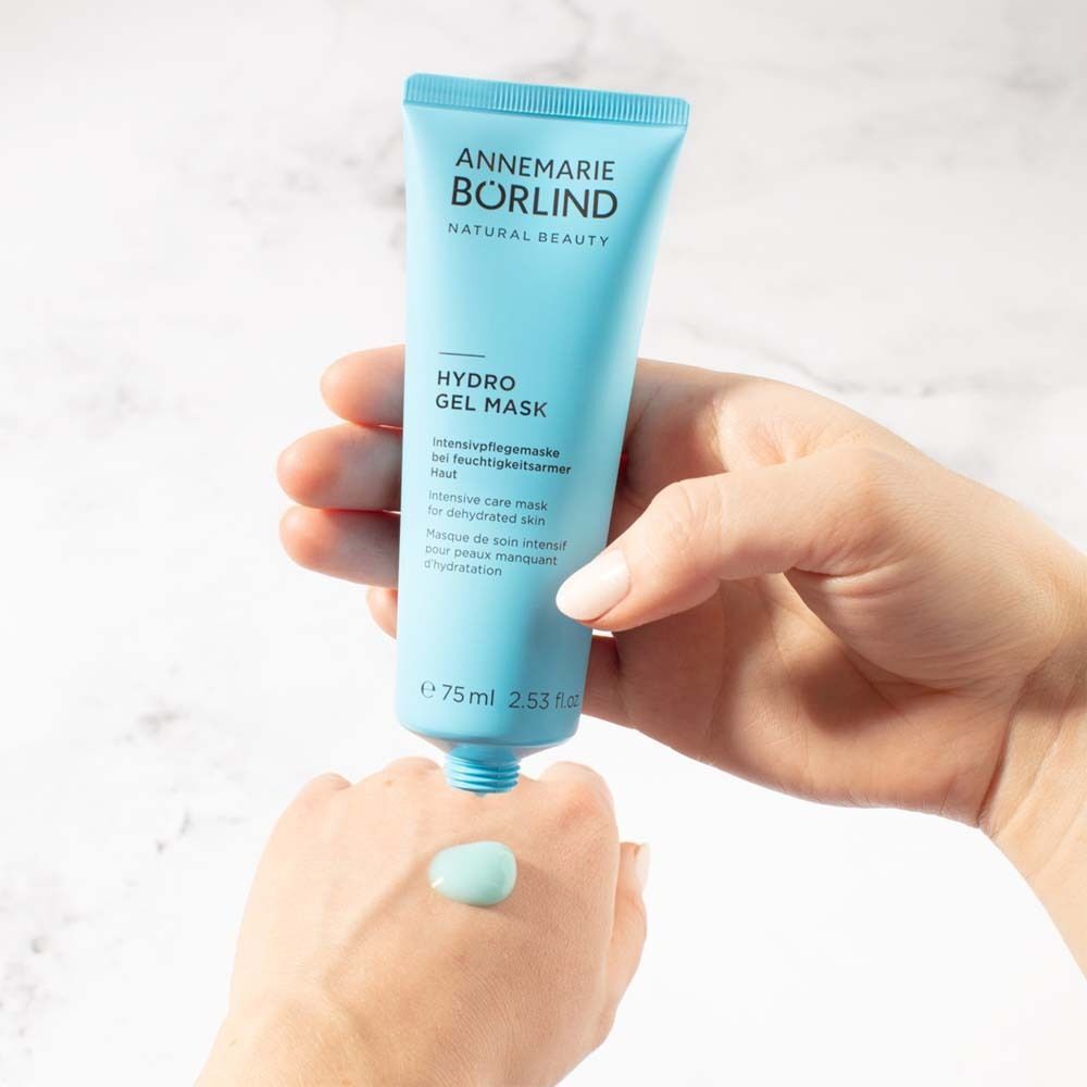 Hand drückt hellblaue Tube ANNEMARIE BÖRLIND Hydro Gel Mask aus, Gel auf Handfläche.