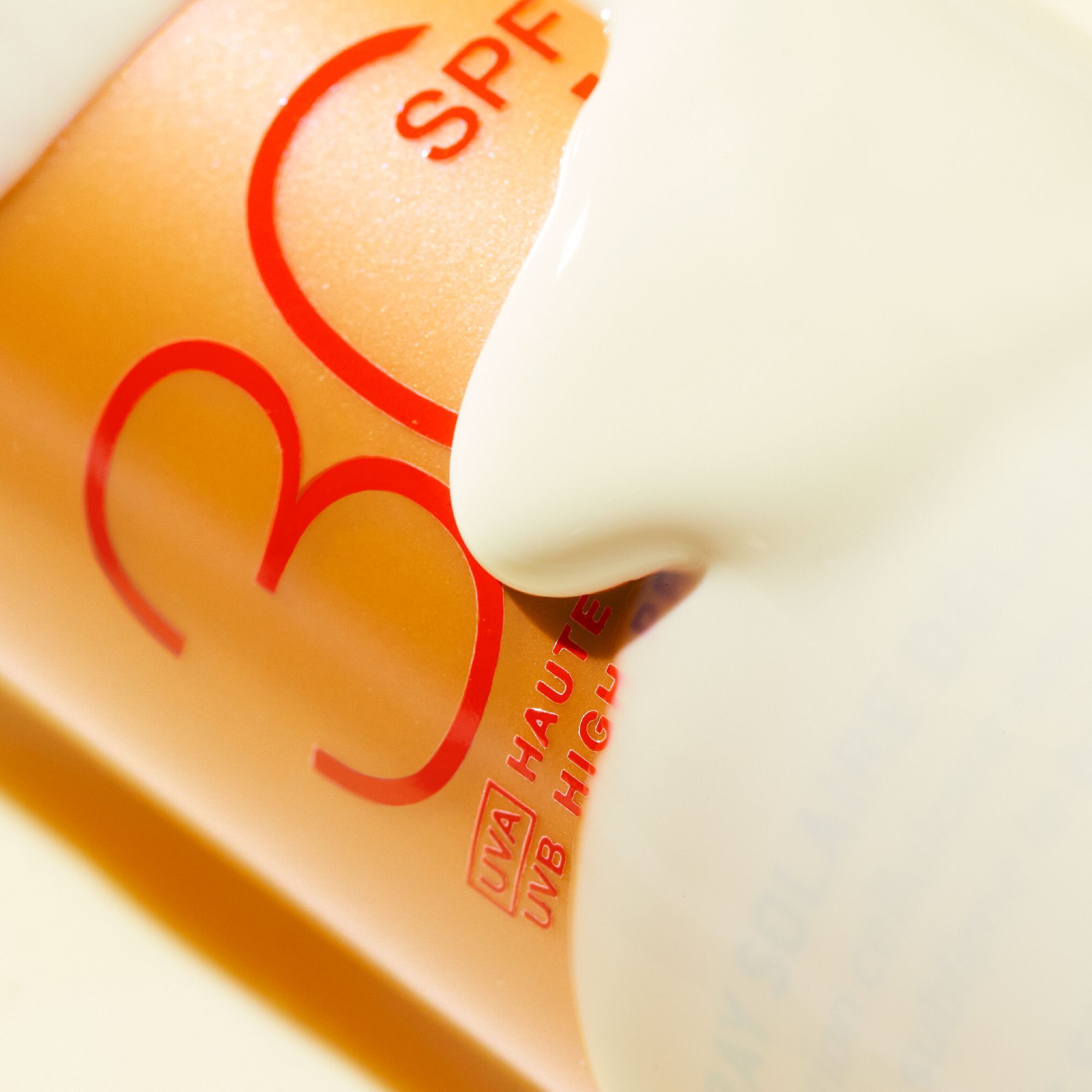 Nahaufnahme einer Sonnencreme-Flasche. Aufschrift SPF 30. Creme wird herausgedrückt.