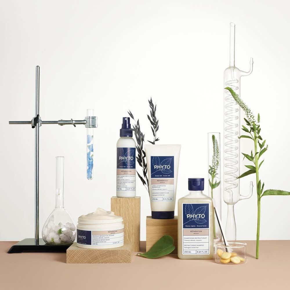 Verschiedene PHYTO PARIS Produkte auf Holzblöcken. Flaschen, Tiegel und Sprays. Laborutensilien und Pflanzenarrangements.