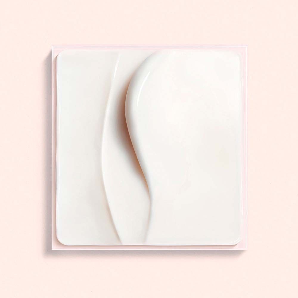 Nahaufnahme einer weißen Creme auf rosa Hintergrund. Creme-Textur mit zwei wellenförmigen Streifen.