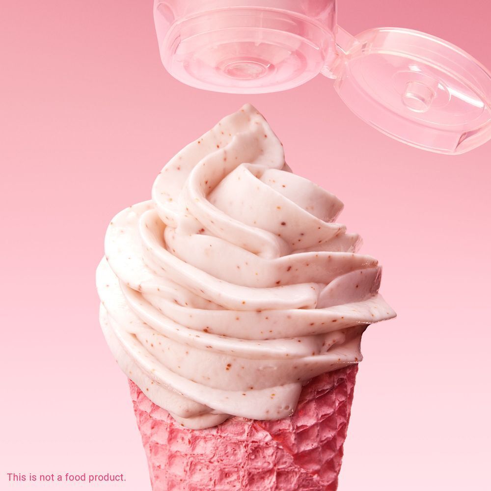 Rosa Waffel mit Creme. Creme-Strudel mit kleinen Partikeln. Deckel einer Tube darüber. Text: This is not a food product.