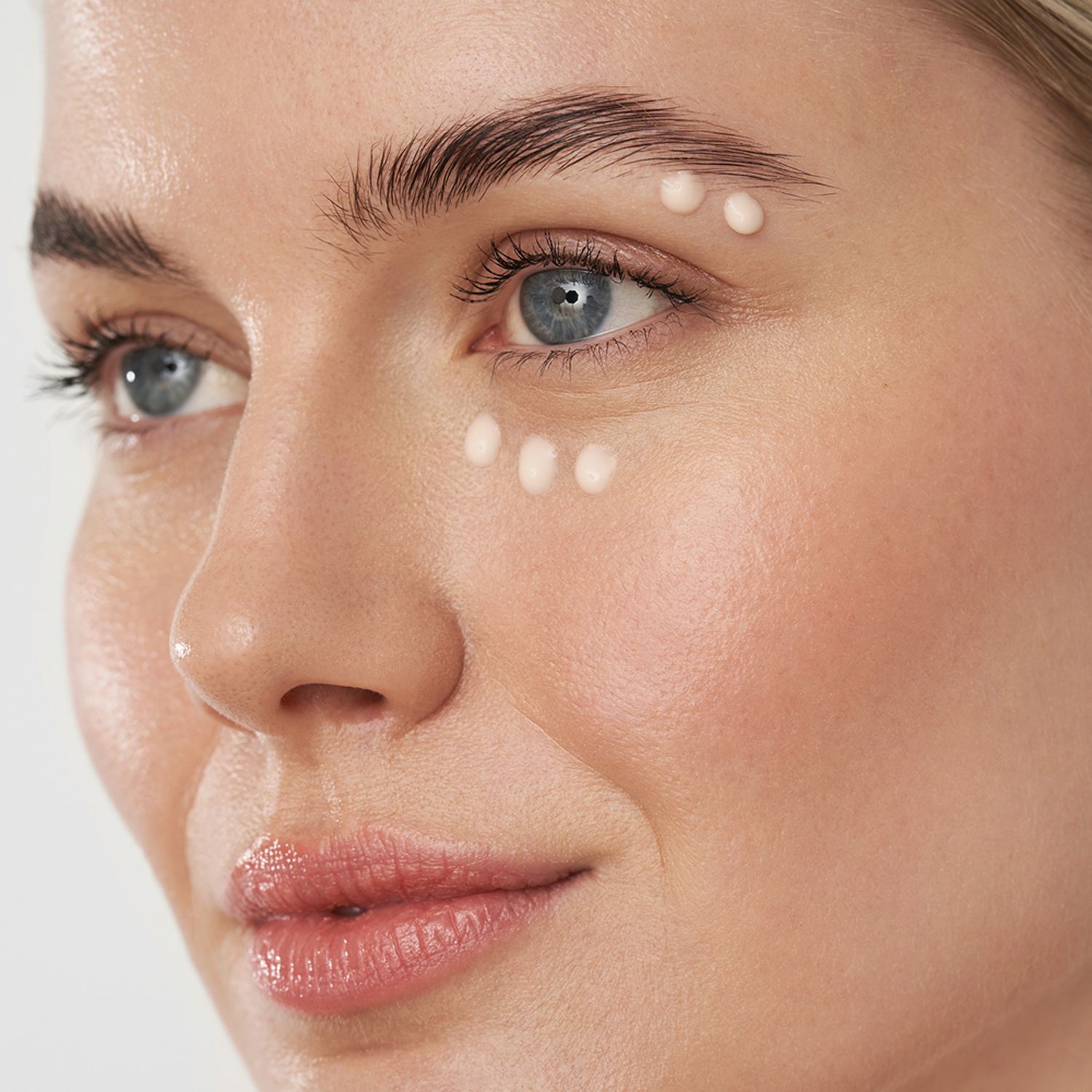 Frauengesicht mit Tupfern von ANNEMARIE BÖRLIND Rose Nature Cooling Spa Eye Cream Gel um die Augenpartie.