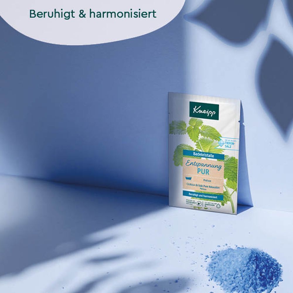 KNEIPP Badekristalle Entspannung Pur. Produktverpackung vor blauem Hintergrund. Blaue Badekristalle daneben.