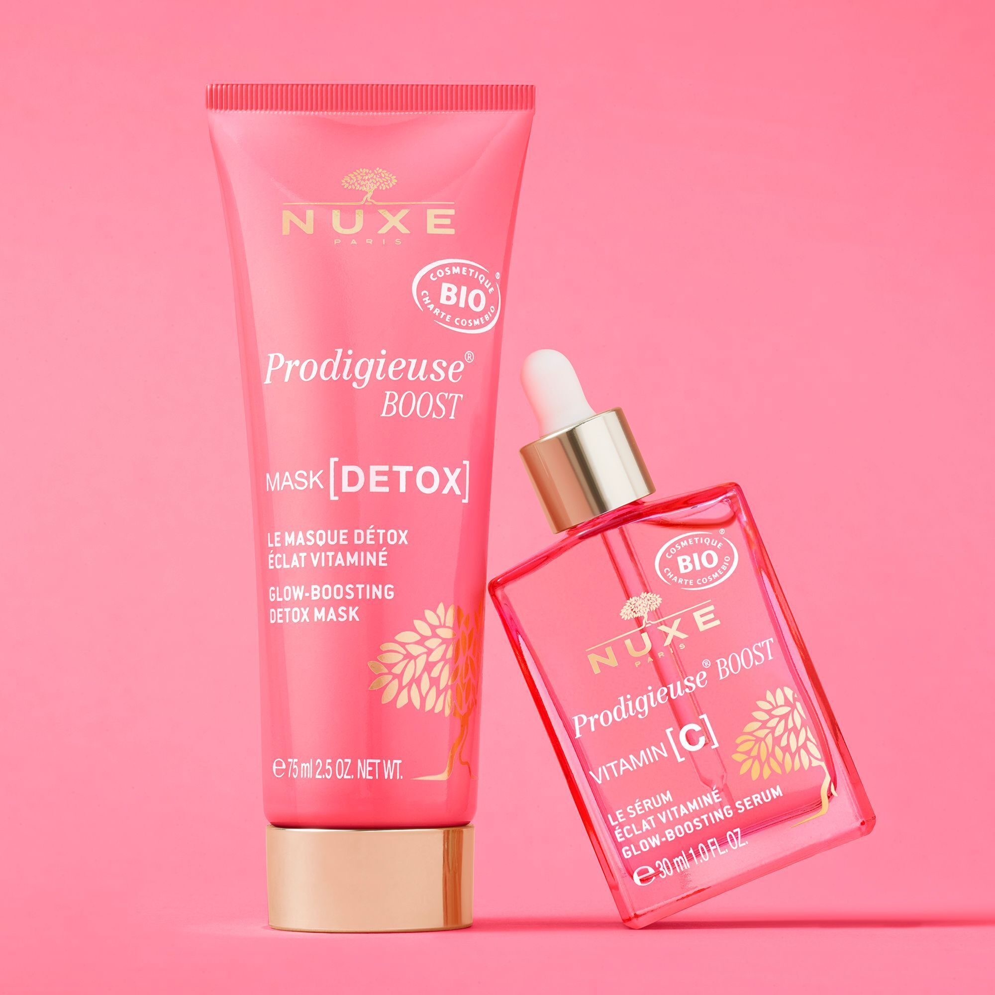 Rosa Tube und Flasche mit goldfarbenen Verschlüssen. Text: "NUXE Paris", "Prodigieuse Boost", "Mask [Detox]" und "Vitamin C".
