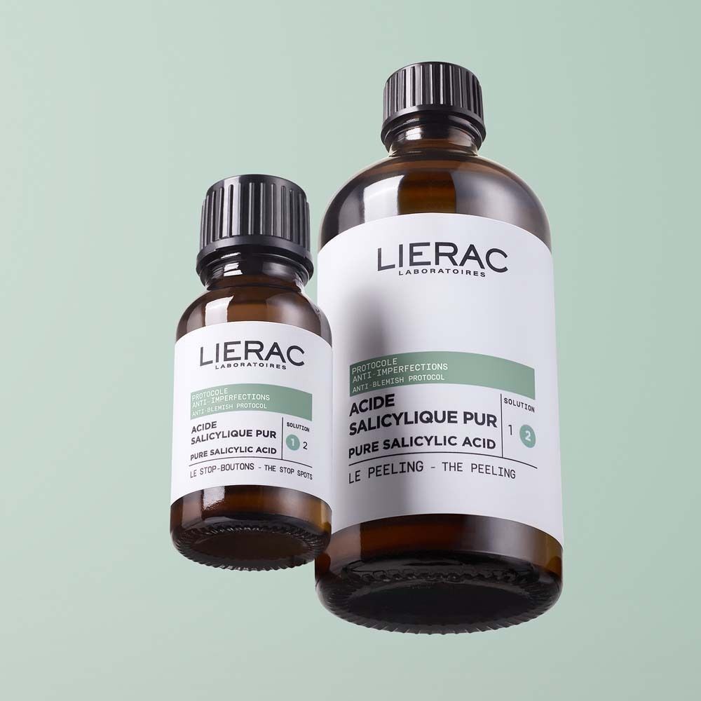 Zwei braune Glasflaschen mit schwarzem Deckel. Etikett mit Produktnamen und Text: PROTOCOLE ANTI-IMPERFECTIONS, ACIDE SALICYLIQUE PUR, LIERAC. Eine Flasche ist kleiner.