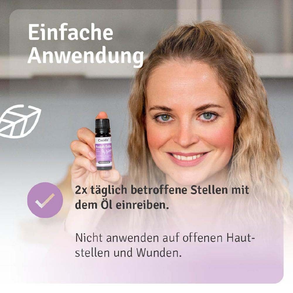 Frau hält eine Flasche Casida® Muskat.-Salbeiöl. Violettes Etikett mit Produktnamen und Logo. Schwarzer Deckel. Anwendung.