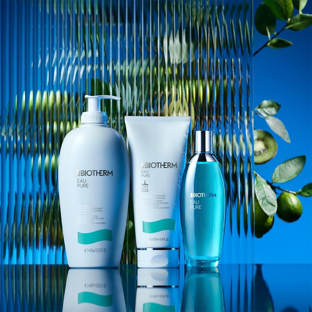 Drei Produkte: Flasche, Tube, Flakon. Weiß und blau. BIOTHERM, Eau Pure. Hintergrund: blau, strukturiert. Dekoration: Kiwi, Blätter.