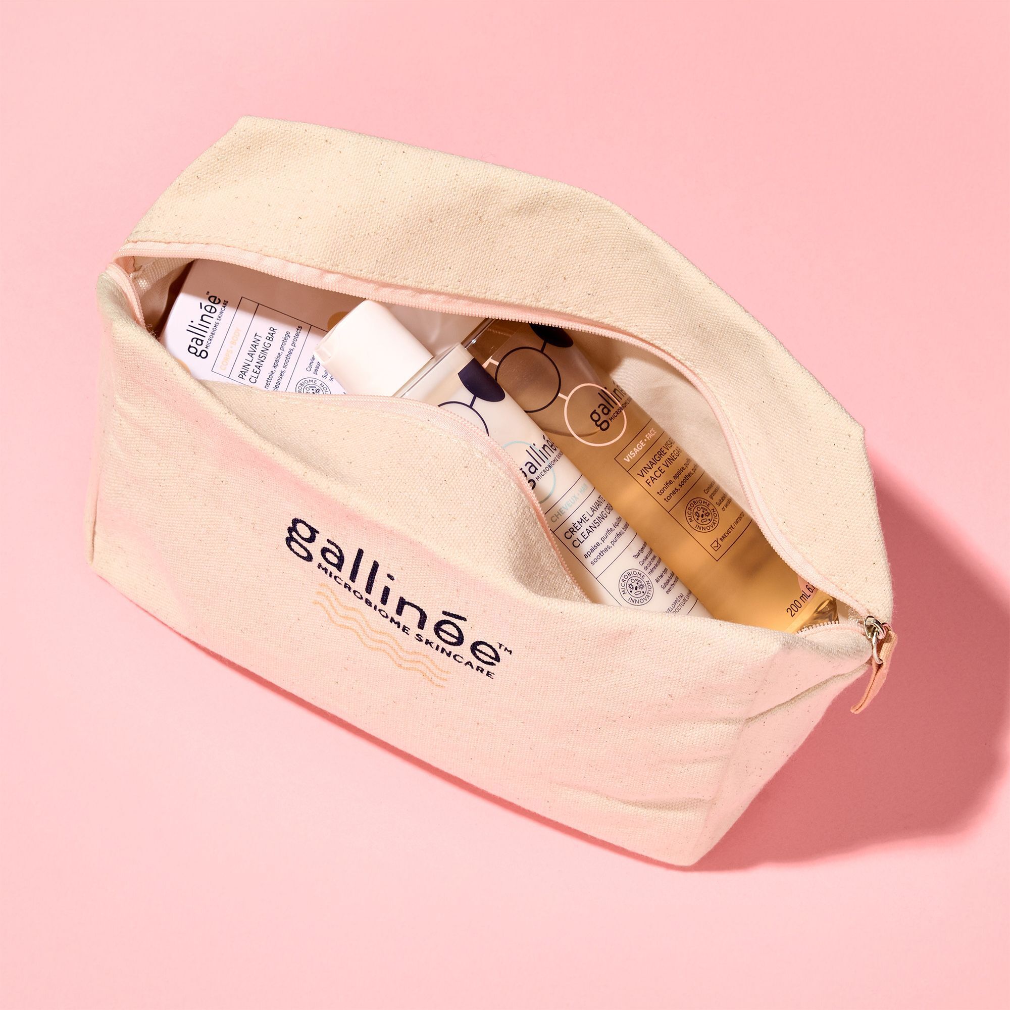 Offene Kosmetiktasche mit Produkten. Enthält Flaschen und eine Seife. Aufschrift: gallinée.