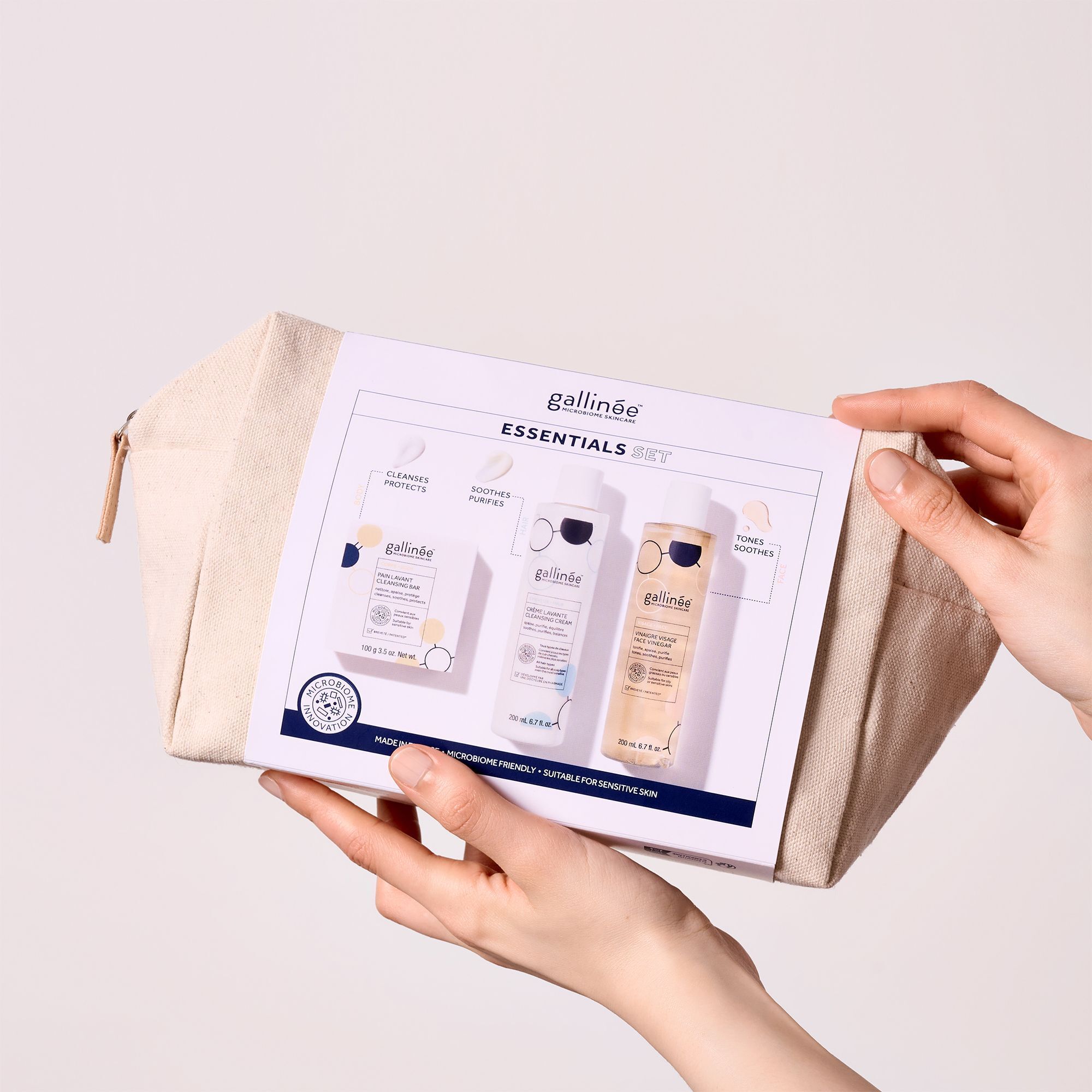 Hände halten ein Set mit Kosmetiktasche, Seife und zwei Flaschen. Aufschrift: gallinée ESSENTIALS SET.