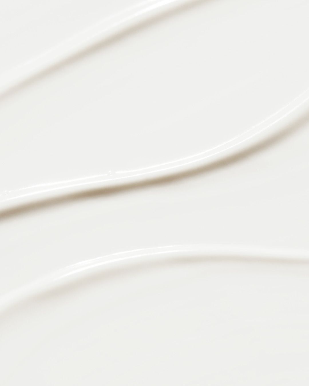 Nahaufnahme von weißer Creme. Die Creme ist in sanften Wellen aufgetragen.