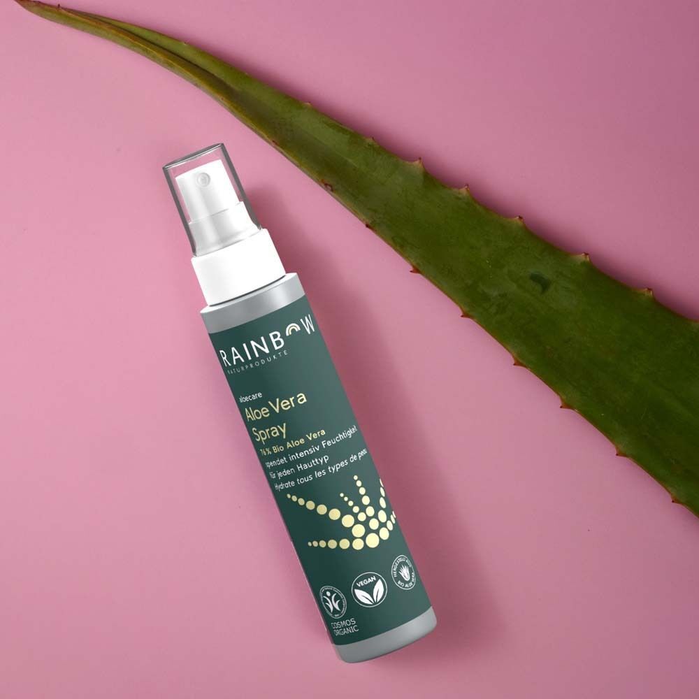 Aloe Vera Spray neben einem Aloe Vera Blatt. Grüne Flasche mit weißem Sprühkopf. Vegan- und Cosmos Organic-Siegel.