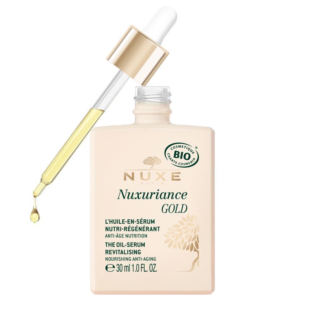 Ein quadratischer Flakon NUXE Nuxuriance Gold Öl-Serum mit goldfarbenem Deckel und Pipette. Tropfen Öl. Aufschrift: Nuxuriance GOLD, L'HUILE-EN-SÉRUM, e 30 ml.