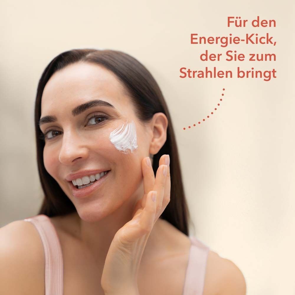 Frau mit weißer Creme auf der Wange. Text: Für den Energie-Kick, der Sie zum Strahlen bringt.