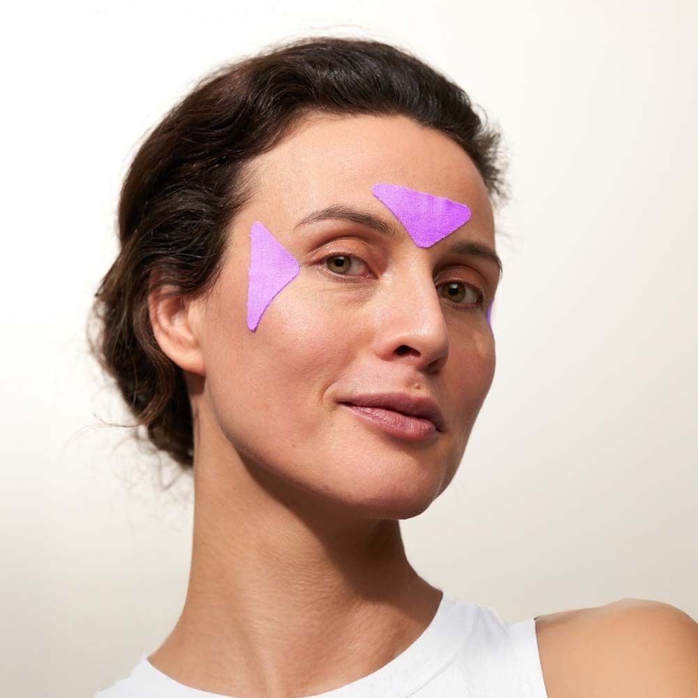 Frau mit zwei lila, dreieckigen Facial Patches auf der Stirn und an der Seite des Gesichts.