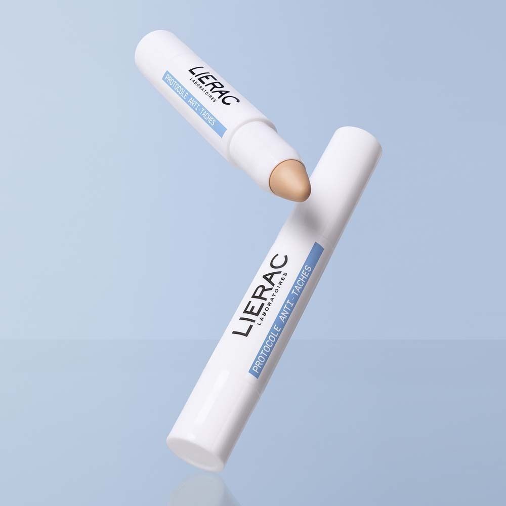 Zwei weiße Stifte, einer mit beigefarbener Spitze. Aufschrift: LIERAC, Protocole Anti-Taches, Vitamine E, Le Stick, Solution.
