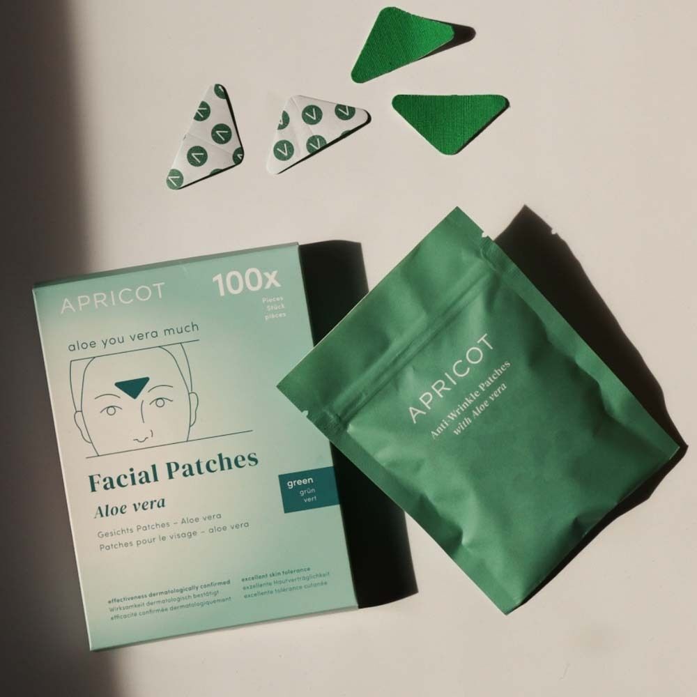 Verpackung und Beutel Gesichtspatches. Grün. Aufschrift: APRICOT, Facial Patches, Aloe vera. Dreieckige Patches.