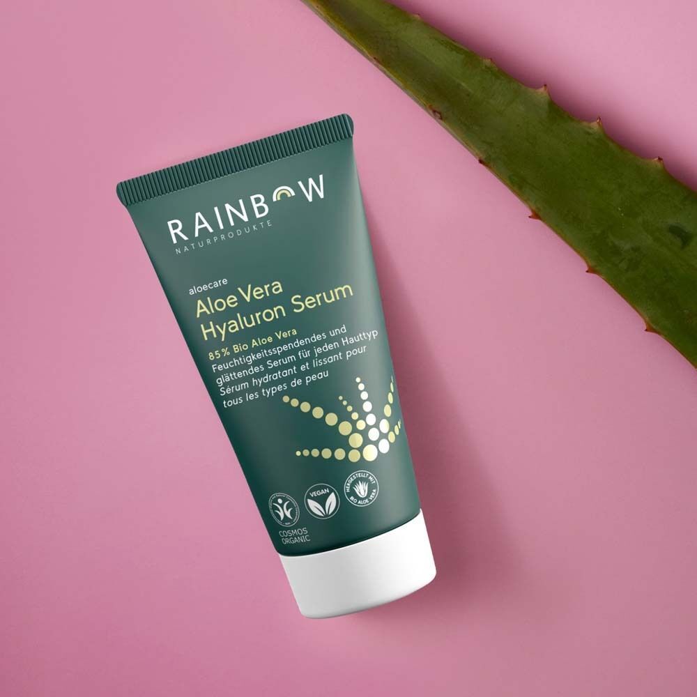 Tube Aloe Vera Hyaluron Serum. Grün-weiße Verpackung. Produktname und Logos. Vegan- und Cosmos Organic-Siegel. Auf rosa Untergrund.