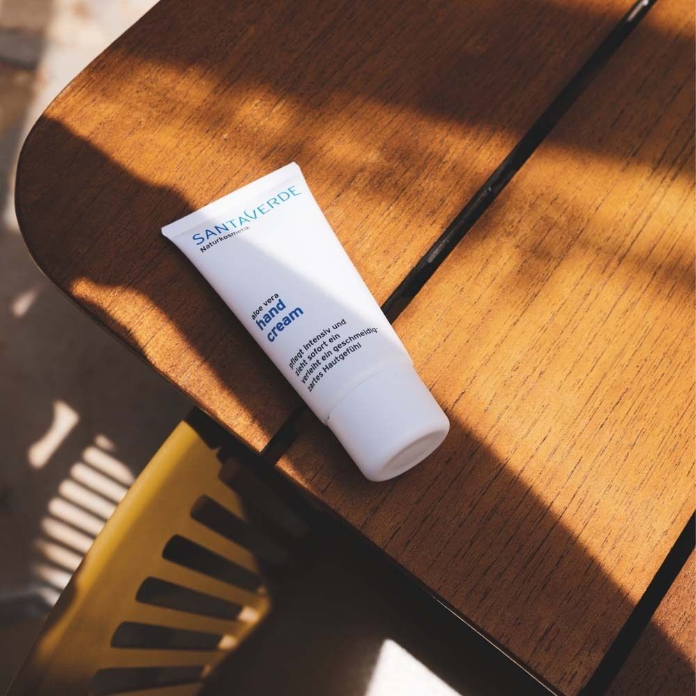 Weiße Tube Handcreme auf Holzoberfläche. Aufschrift: SANTAVERDE, Hand Cream. Text: intensiv pflegend und schnell einziehend.