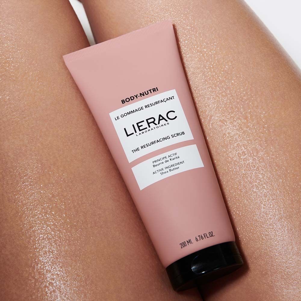 Rosa Tube Körperpeeling auf Haut. Schwarzer Deckel. Text: BODY-NUTRI, LIERAC, THE RESURFACING SCRUB, 200 ml.