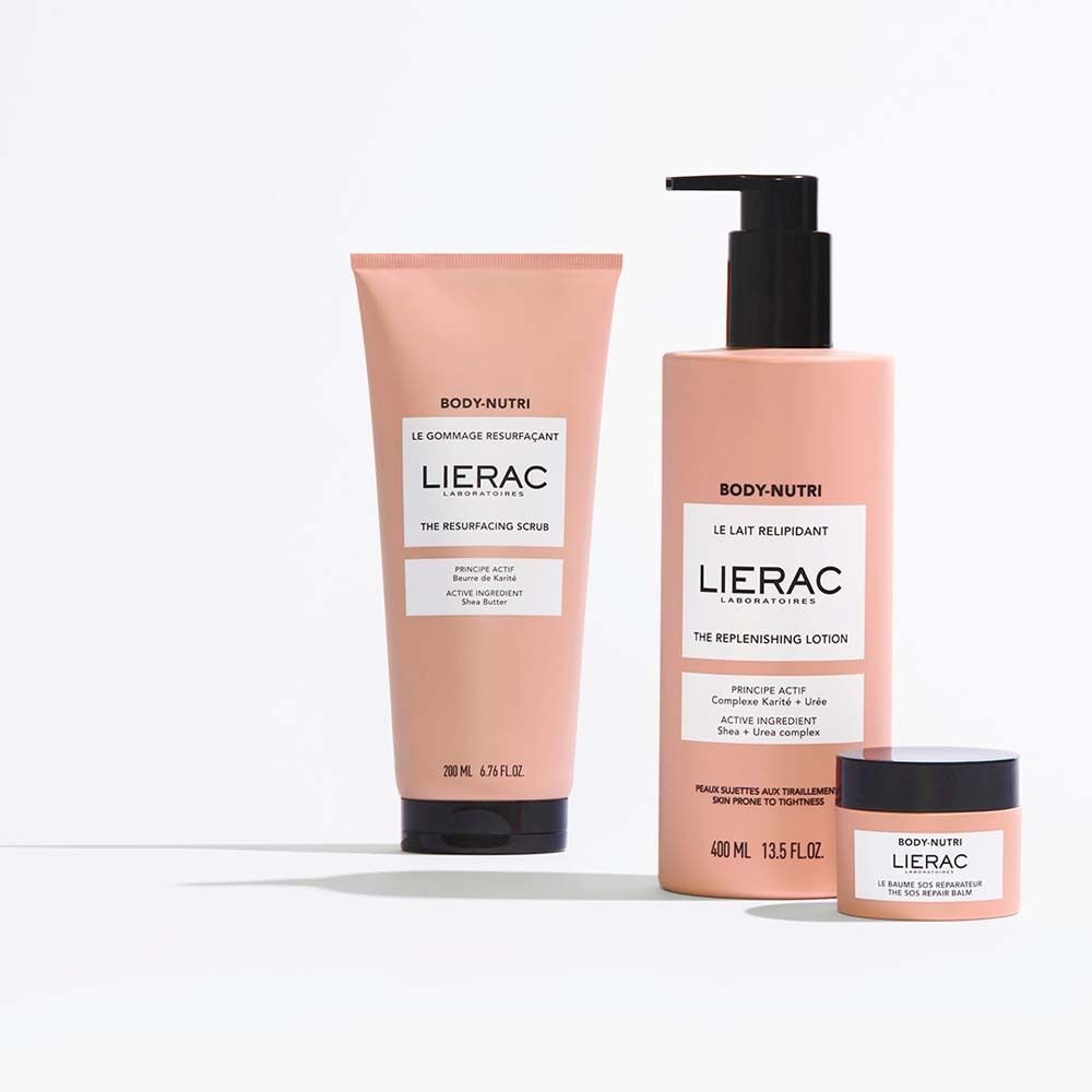Drei Produkte: Tube, Flasche, Tiegel. Rosa Verpackung. Text: BODY-NUTRI, LIERAC, THE RESURFACING SCRUB, LE LAIT RELIPIDANT.