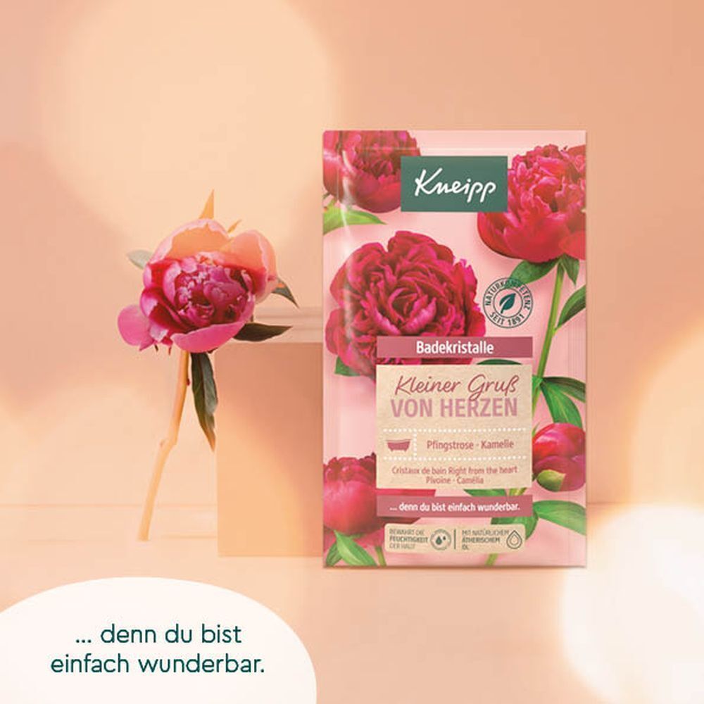 Produktverpackung mit Blüten und Text: Kneipp, Badekristalle, Kleiner Gruß von Herzen. Eine Blüte liegt daneben.