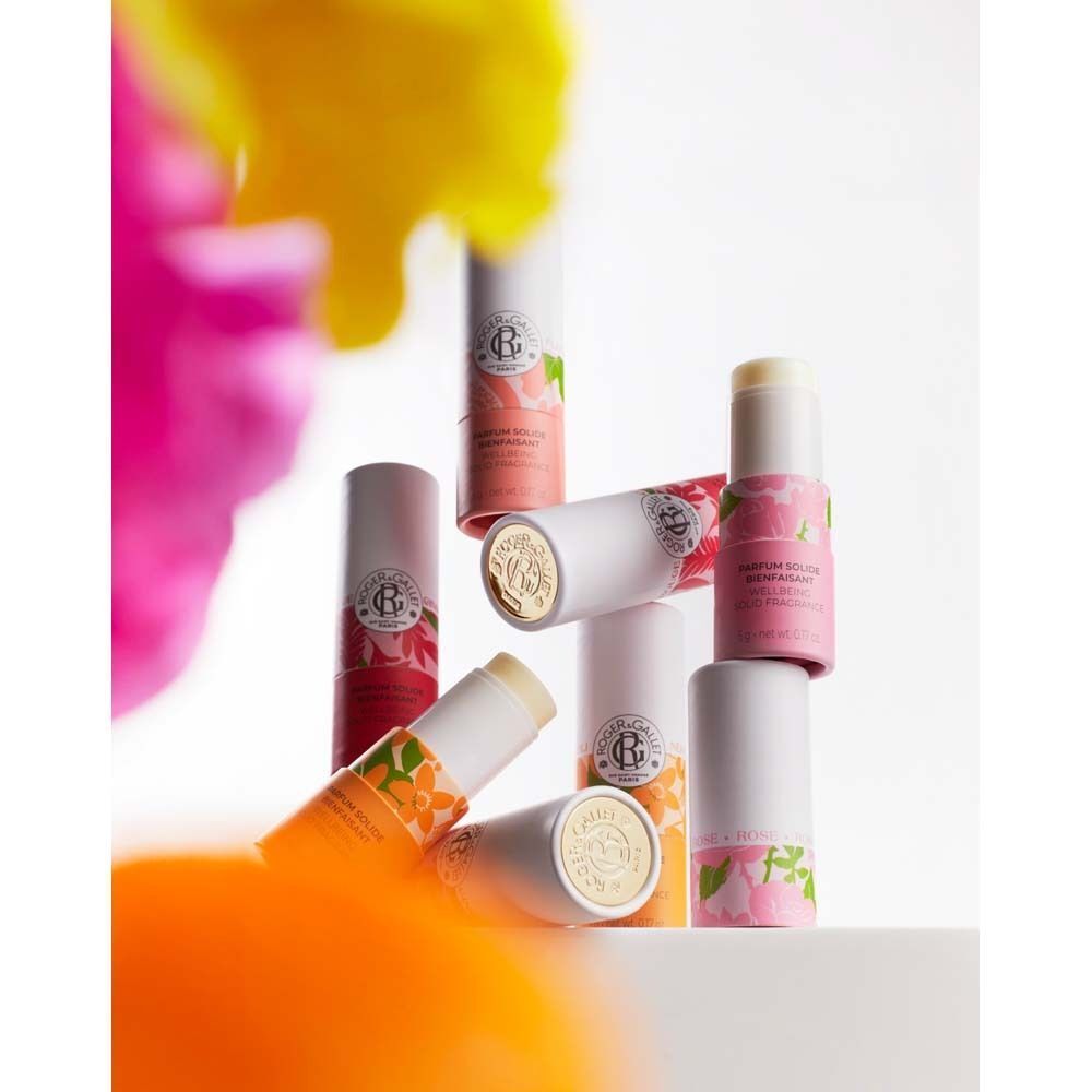 Mehrere Parfumsticks, teilweise angeordnet. Weißer Deckel, roter Boden mit floralem Muster. Text: PARFUM SOLIDE BIENFAISANT.