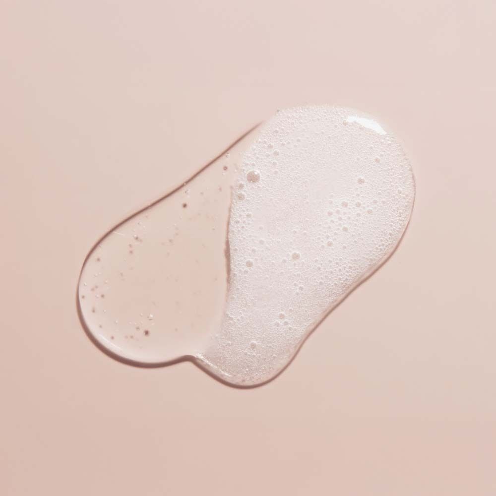 Nahaufnahme von Shampoo-Schaum. Flüssigkeit und Schaum auf rosa Hintergrund.