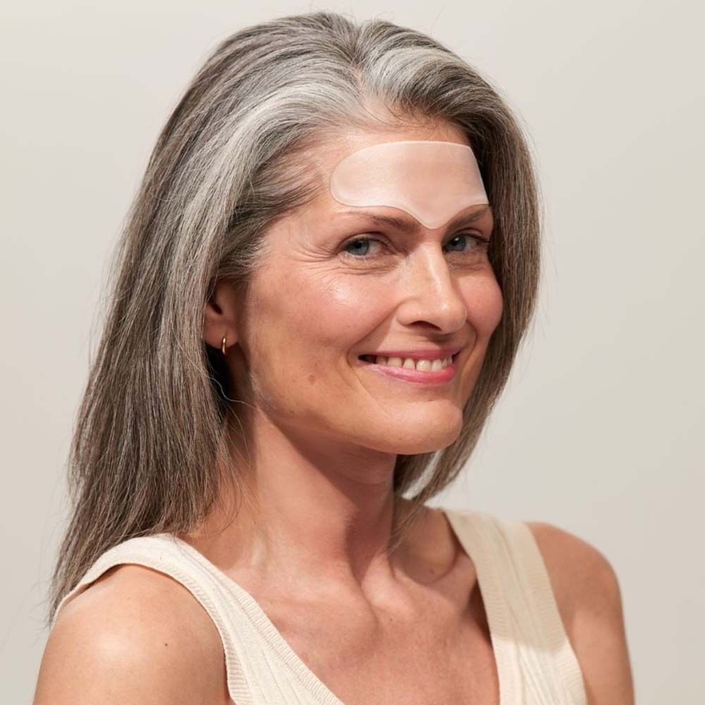 Frau mit Stirn Pad auf der Stirn. Transparentes Pad. Graue Haare.