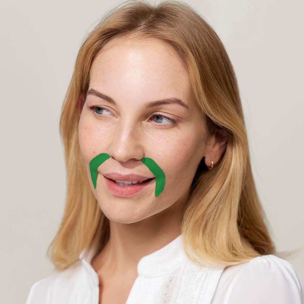 Frau mit blonden Haaren, die grüne Mundpflaster trägt. Pflaster sind um die Lippen angebracht.