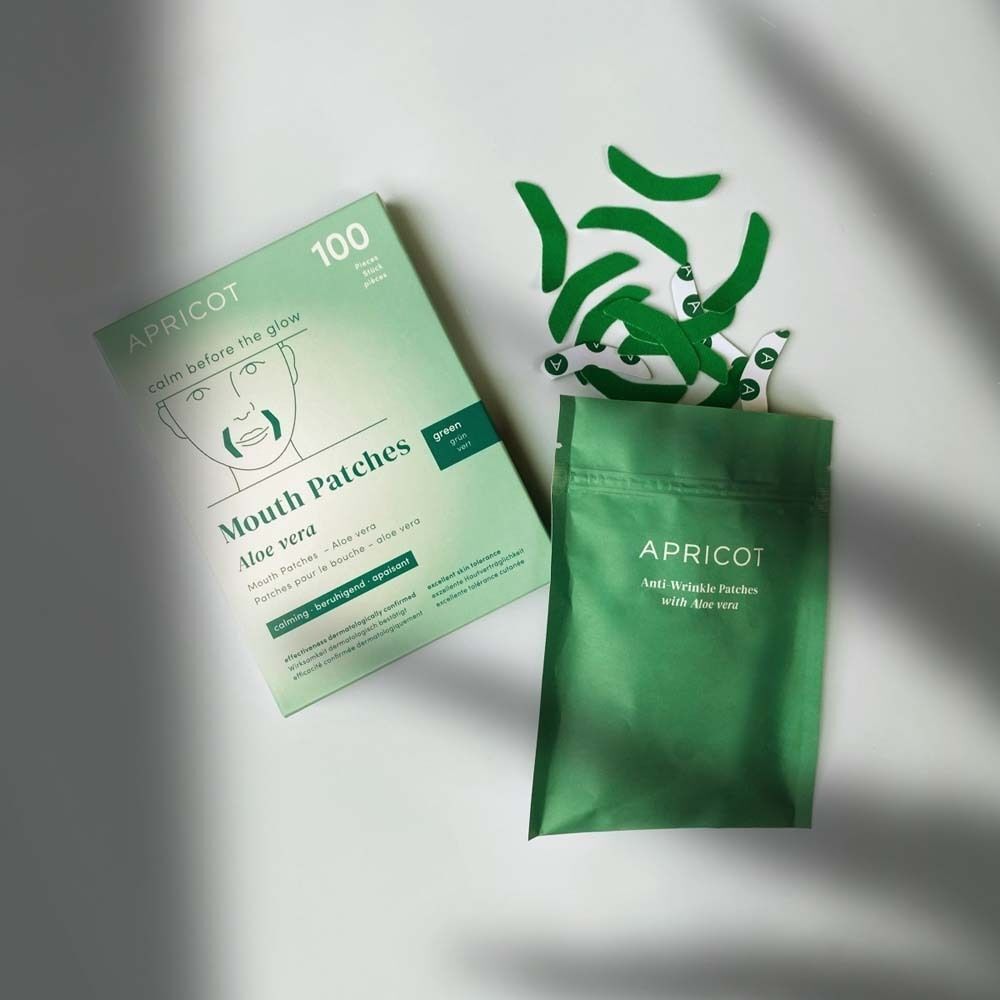 APRICOT Mouth Patches Aloe vera Packung und Beutel. Daneben liegen grüne Mundpflaster. Produktname und Logo.