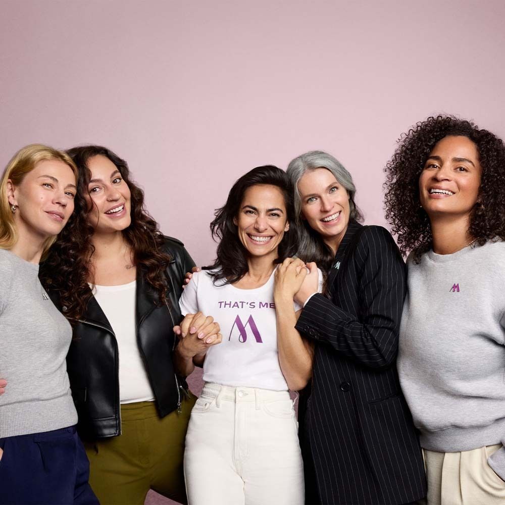 Fünf Frauen stehen zusammen. Auf ihren Shirts ist ein Logo abgebildet.