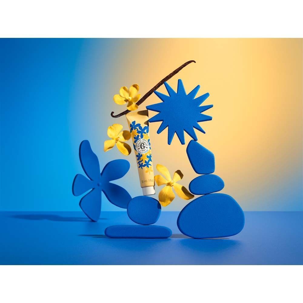 Handcreme-Tube zwischen blauen und gelben Dekorationen. Aufschrift: Vanille Soleil.