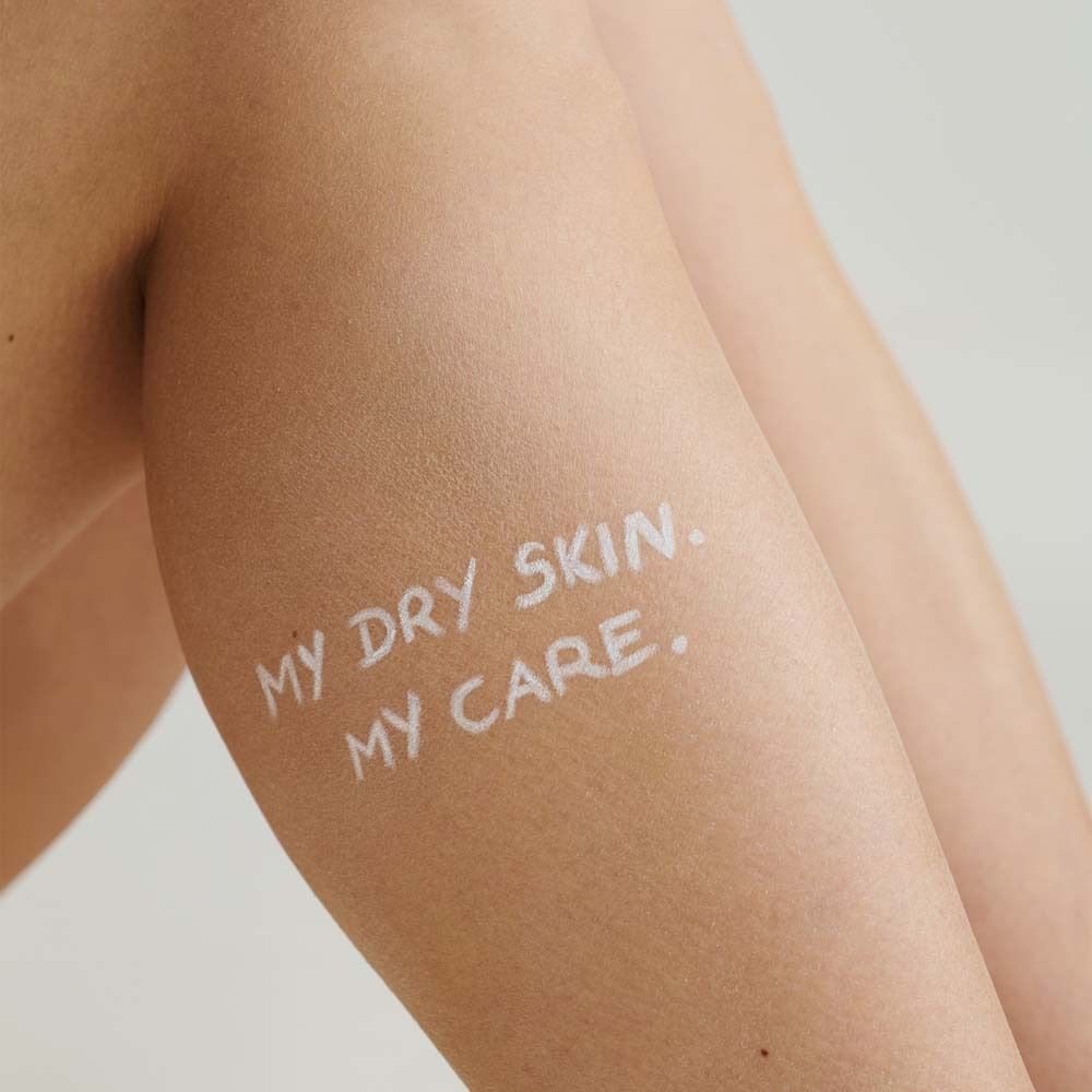 Arm mit weißer Schrift: MY DRY SKIN. MY CARE. Haut mit Text beschriftet.