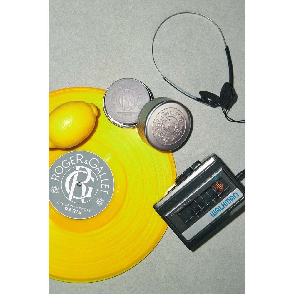 Graue Rasierseife, gelbe Schallplatte, Kopfhörer und Walkman. Auf der Seife ist ein Logo zu sehen. Die Platte hat ein Logo.