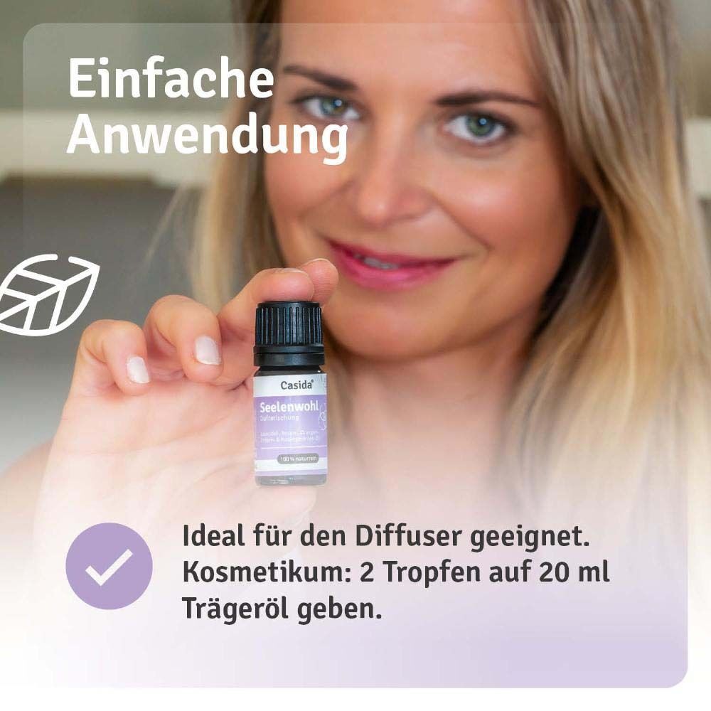 Frau hält Flasche Casida® Seelenwohl. Violettes Etikett, schwarzer Deckel. Text: Ideal für den Diffuser geeignet. Kosmetikum: 2 Tropfen auf 20 ml Trägeröl.