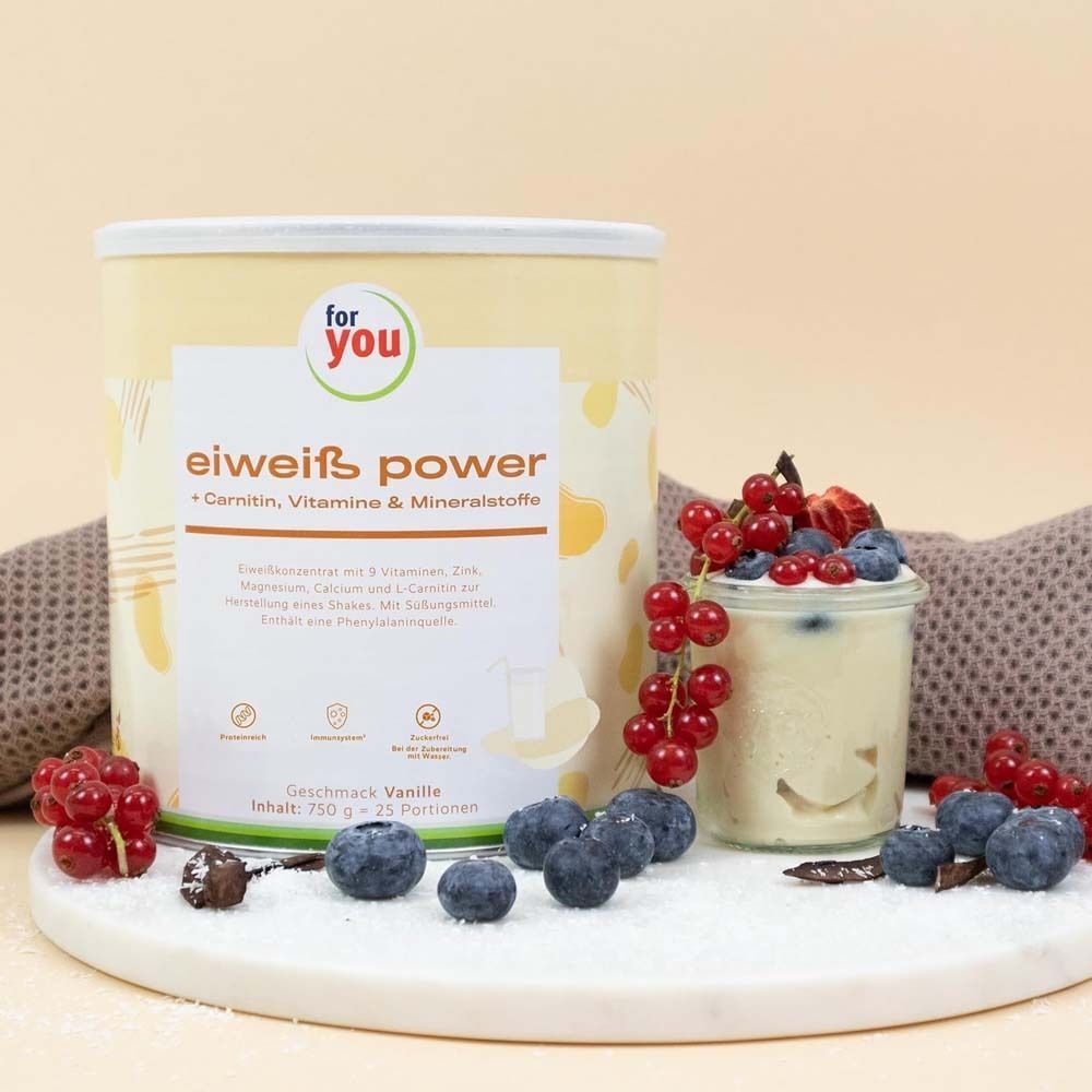 Dose 'For you' Eiweiß Power Vanille neben einem Glas mit Beeren. Aufschrift: Carnitin, Vitamine & Mineralstoffe. Auf weißem Untergrund.