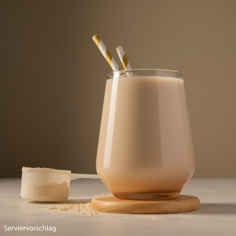 Glas mit Proteinshake, Löffel. Proteinshake in einem Glas. Löffel mit Proteinpulver. Servierbeispiel.