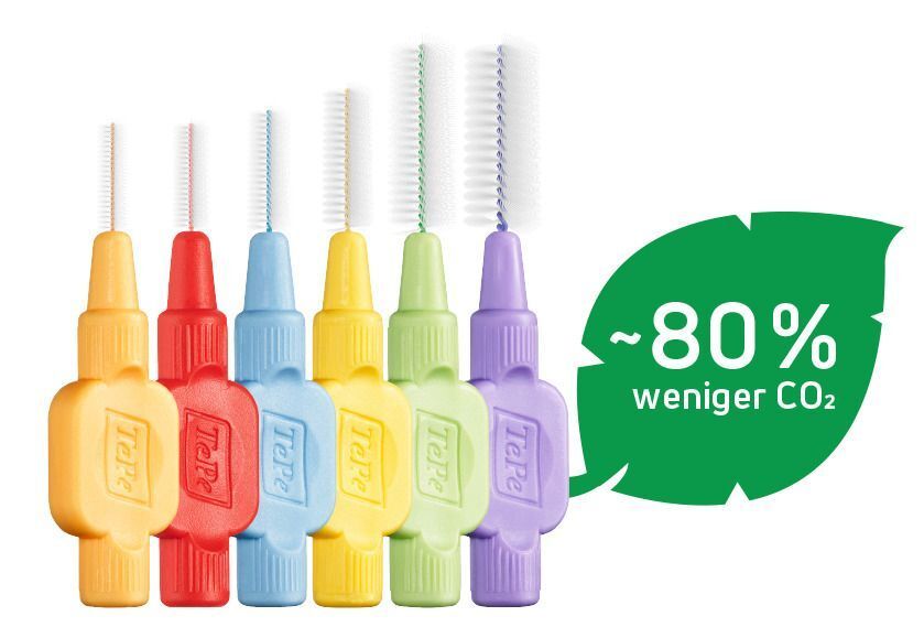 Verschiedene farbige Interdentalbürsten mit weißen Borsten. Ein grünes Blatt mit der Aufschrift ~80% weniger CO2.
