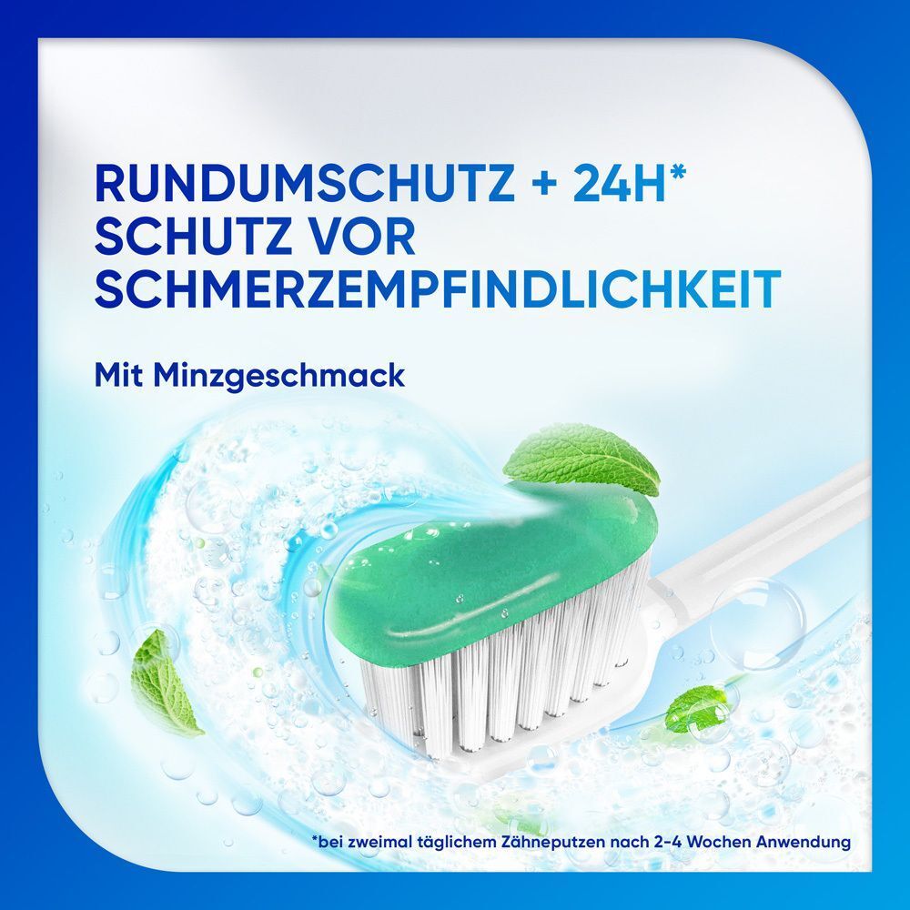 Zahnbürste mit Zahnpasta. Grüne Zahnpasta auf weißen Borsten. Hintergrund: blau. Text: Rundumschutz + 24H* Schutz vor Schmerzempfindlichkeit.