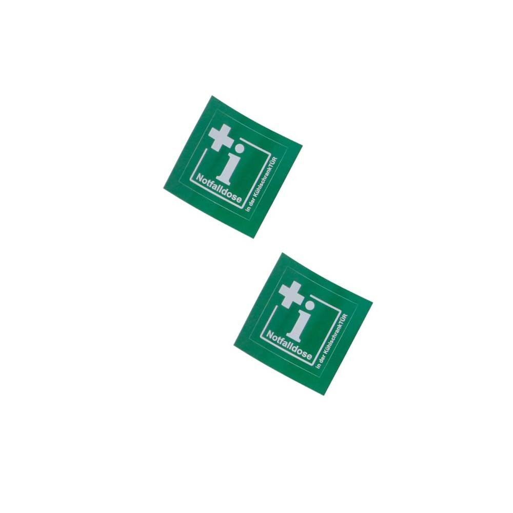 Zwei grüne quadratische Aufkleber mit weißem Kreuz und i. Aufschrift: Notfalldose, i in der Kühlschranktür.